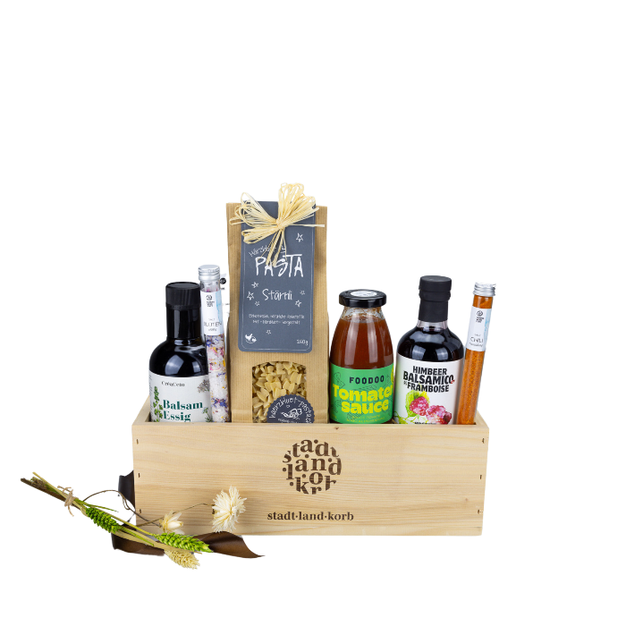 Balsamessig, Blütenzauber im Reagenzglas, Stärnli Pasta von Härzbluet Pasta, FOODOO tomatensauce, Himbeer Basamico und Chili Salz im Reagenzglas in einem Stadt Land Korb Holzkorb vor weissem Hintergrund.