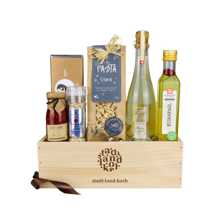 Genuss Oase Alkoholfrei Geschenkkorb vor weissem Hintergrund befüllt mit Tomatenpesto, Champagner Salz, Taucherli Gold Schokolade, Stärnli Pasta, Tröpfel der ERSTE, Rosmarinöl