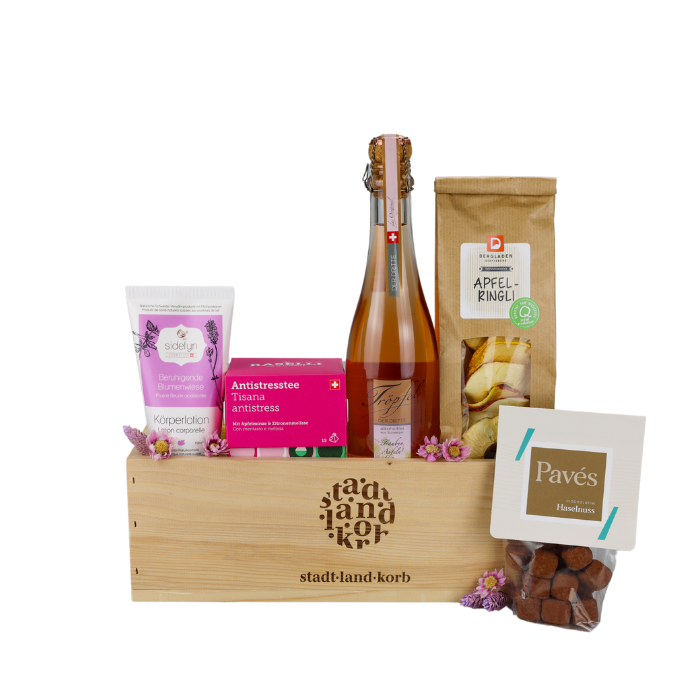 Genuss für die Sinne Geschenkkorb vor weissem Hintergrund befüllt mit Sidefyn Körperlotion, Antistresstee, Tröpfel der Dritte, Apfelringli und Haselnuss Pavés