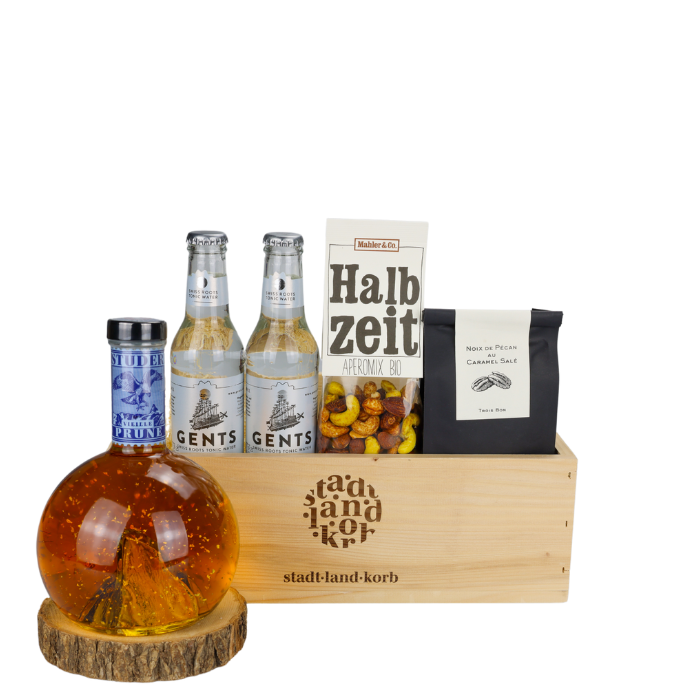 Goldener Tropfen Geschenkkorb vor weissem Hintergrund befüllt mit Swiss Gold Prune, Gents Swiss Tonic, Halbzeit Apero Mix, Noix de Pécan au Caramel Salé