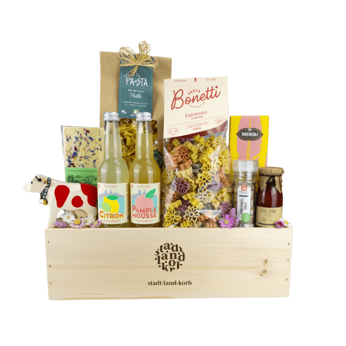 Happy Family Geschenkkorb vor weissem Hintergrund befüllt mit Trauffer Kuh, weisser Schokolade, Bio Limonade, Pasta, Edelweiss Pasta, Taucherli Schokolade, Chrüsimüsi Salz, Tomatenpesto