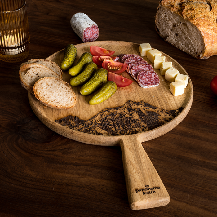 Pilatus Apéro-Platte mit Brot, Gewürzgurken, omaten, Salami und Käse auf Holztisch