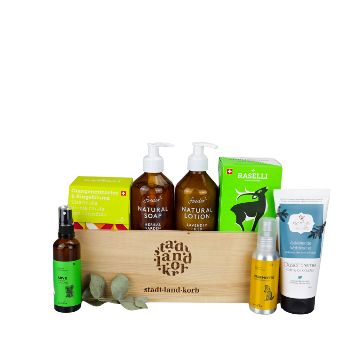 Pure Auszeit Geschenkkorb vor weissem Hintergrund befüllt mit Tee, Arve Raumspray, Soeder Natural Soap & Natural Lotion, Marmotte Massageöl und Sidefyn Duschcreme
