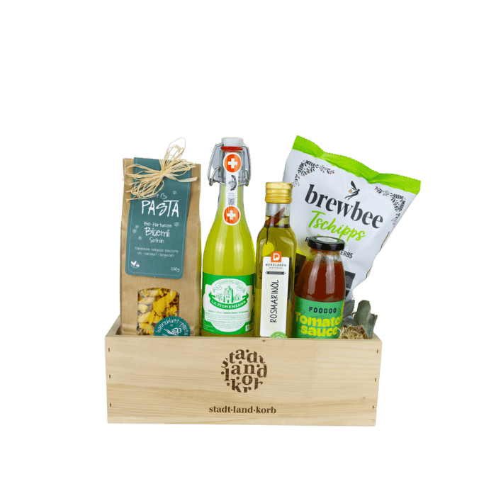 Rosmarin Geschenkkorb or weissem Hintergrund befüllt mit Safran Blüemli Pasta, Gazosa, Rosmarinöl, Brewbee Tschipps, Foodo Tomatensauce