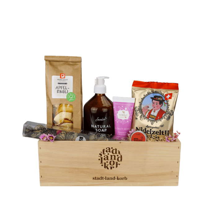 Süsse Erholung Geschenkkorb vor weissem Hintergrund befüllt mit Apfelringli, Teekugeln, Soeder Natural Soap, Sidefyn Handcreme, Natürlicher Bärgmüntschi Lipgloss und Niderzeltli