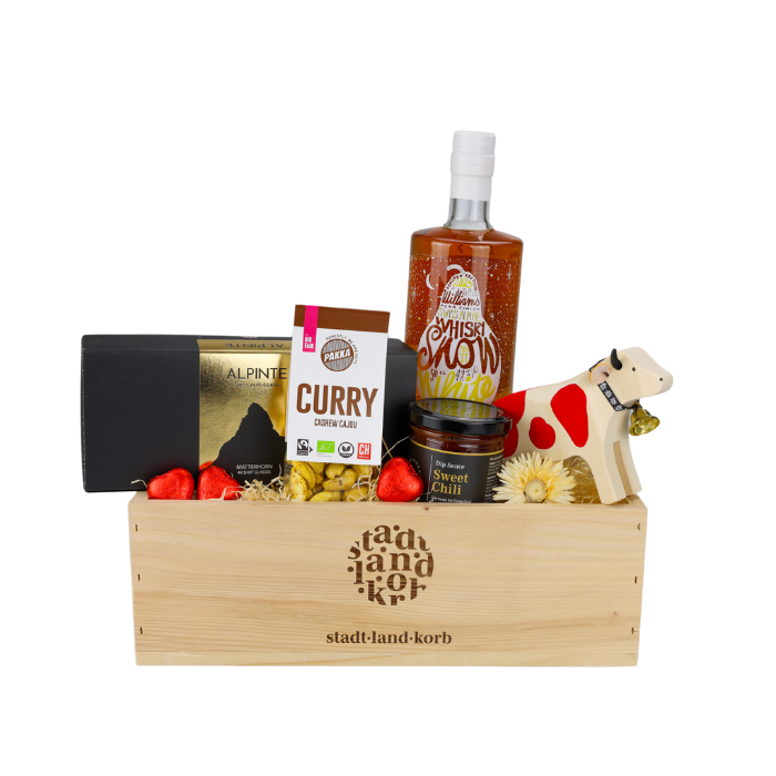 Snow White Säntis Malt Geschenkkorb vor weissem Hintergrund befüllt mit Alpinte Schnappsgläser, Curry Cashews, sweet Chili Dipp, Snow White Säntis Malt Whisky und Trauffer Kuh