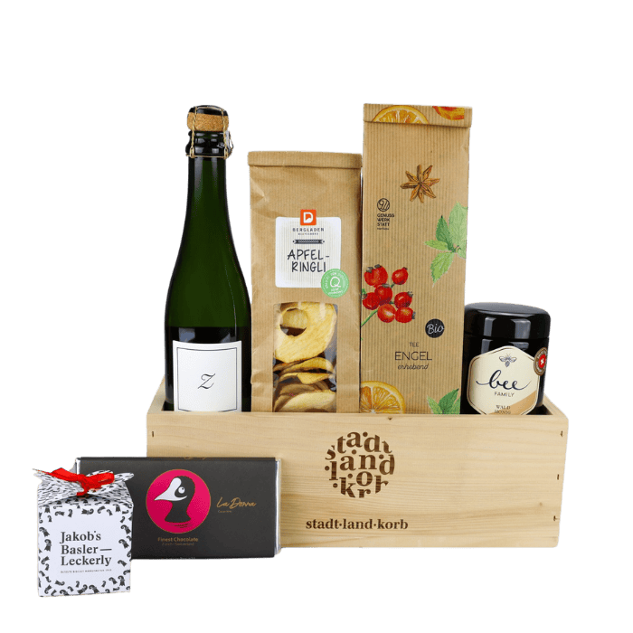 Genusszeit Deluxe Geschenkkorb  vor weissem Hintergrund befüllt mit Zürischümli, Apfelringli, Engeltee, Bee Family Honig, Taucherli Schokolade und Jakob's Basler Leckerly
