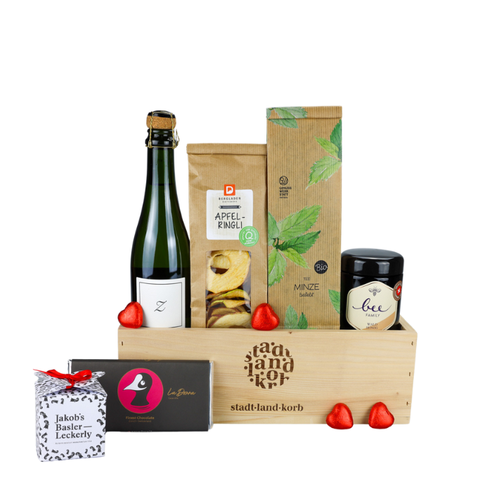 Süsse Auszeit Geschenkkorb vor weissem Hintergrund befüllt mit Zürischümli, Apfelringe, Pfefferminztee, Honig, Taucherli Schokolade, Basler Leckerly und Lindt Herzen