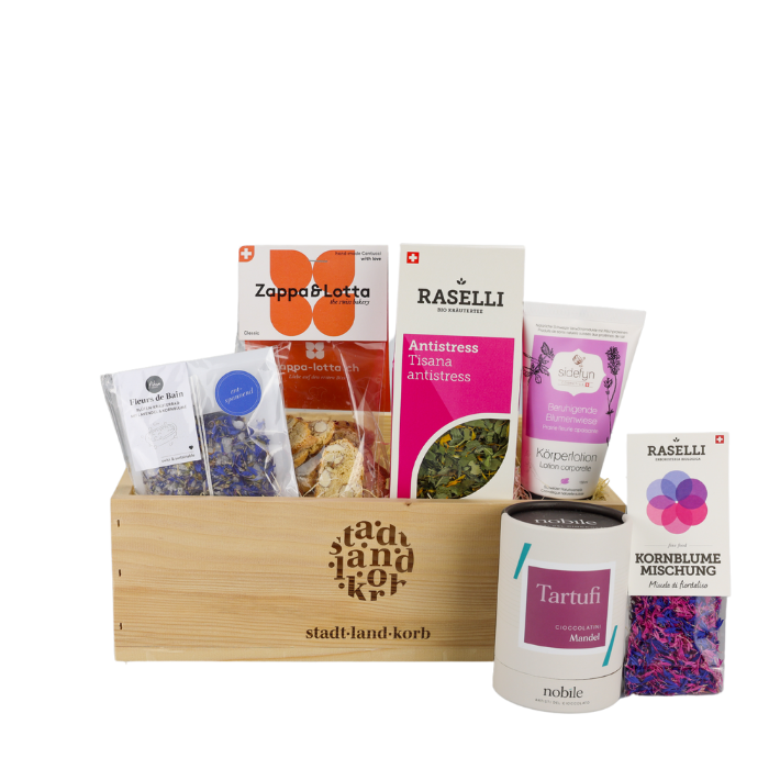 Sweet & Relax Geschenkkorb vor weissem Hintergrund befüllt mit Fleurs de Bain, Cantucchi, Antistress Tee, Sidefyn Körperlotion, essbare Kornblumen, Tartudi