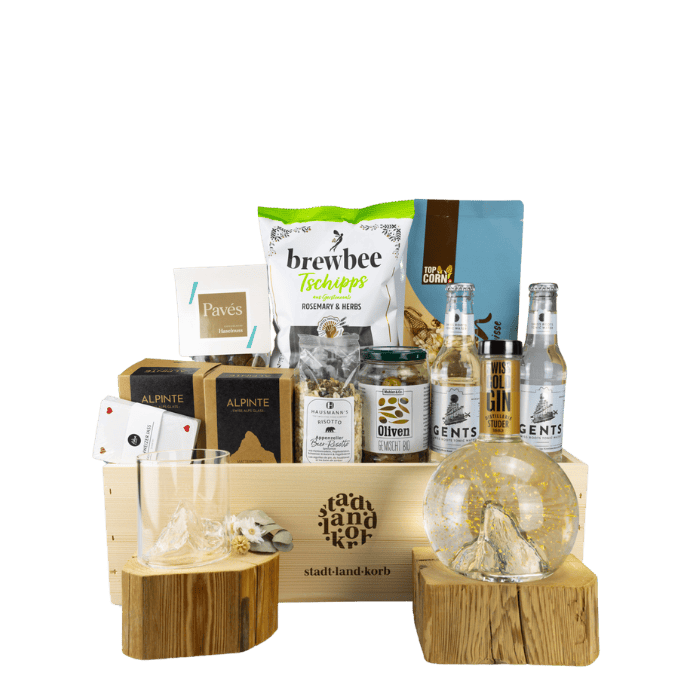 Swiss Gold Gin Premium Geschenkkorb vor weissem Hintergrund befüllt mit Swiss Gold Gin, Tschipps, Pavés, Alpinte Matterhorn oN the Rocks, Popcorn, Tonic, Jasskarten, Oliven und Risotto