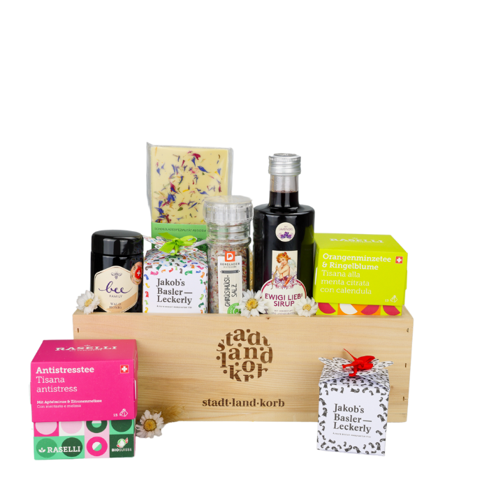 Tee & Zuckerglück Geschenkkorb vor weissem Hintergrund befüllt mit Bio Raselli Tee, Schokolade, Honig, Jakob's Basler Rahmtäfeli, Ewigi Liebi Sirup, Chrüsimüsi Salz und Jakob's Basler Leckerly