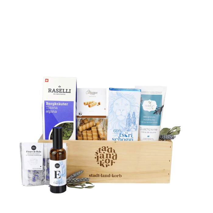 Tiefenentspannt Geschenkkorb vor weissem Hintergrund befüllt mit Raselli Bergräuter Tee, Straumann Hüppen, Tsüri Schokolade, Sidefyn Duschcreme, Fleurs de Baine Badesalz, Energie Spray