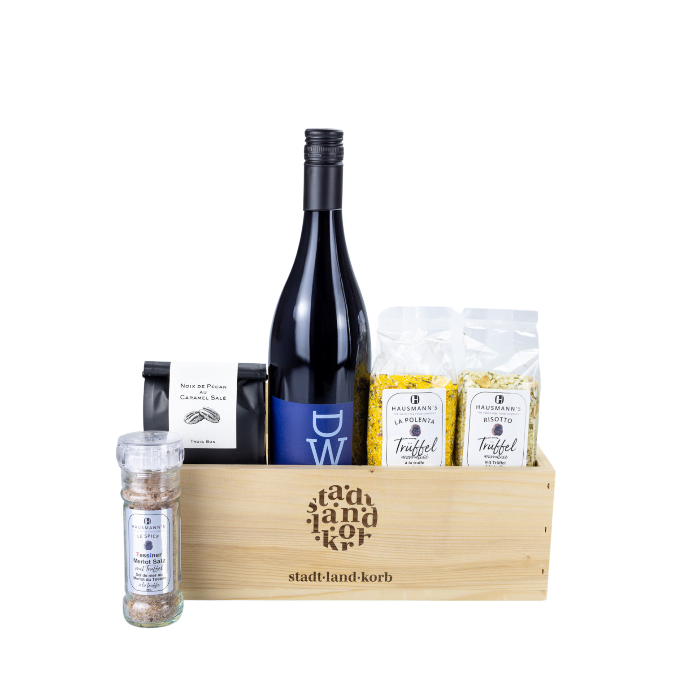 Stadt Land Korb Trüffel Dinner Geschenkkorb befüllt mit Tessiner Merlotsalz, Pécan Nüsse, DW Rotwein, Trüffel Polenta und Trüffel Risotto vor einem weissen Hintergrund.