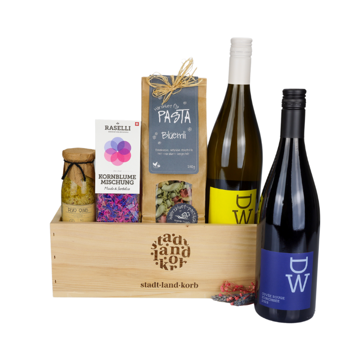 Weinperle Geschenkkorb vor weissem Hintergrund befüllt mit Oliven Pesto, Kornblumen, Blüemli Pasta, DW Weisswein und DW Rotwein