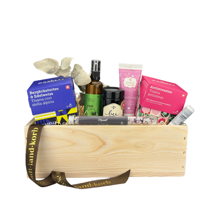 Kleine Auszeit Geschenkkorb befüllt mit Bio Raselli Bergkräuter und Edelweisstee, Arve Raumduft, Bee Family Honig, Sidefyn Handcreme, Bio Raselli Antistresstee, und Badesalz Auszeit. vor weissem Hintergrund.