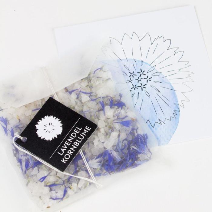Badesalz Fleurs de Bain Lavendel & Kornblume Moodbild mit einer Blumenkarte auf weissem Hintergrund.