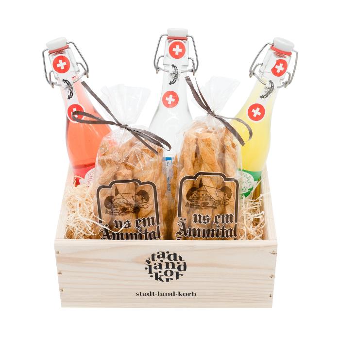 Gazosa Geschenkkorb mit  Gazosa La Fiorenzana All' Arancia Amara, Gazosa La Fiorenzana Al Lampon, Gazosa La Fiorenzana Al Limone und zwei Emmentaler Flutes von Emmentaler Backwaren in einem Stadt Land Korb Geschenkkorb aus Holz. Vor weissem Hintergrund.