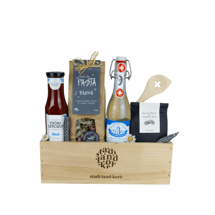 Culinary Passion Geschenkkorb vor weissem Hintergrund befüllt mit Tsüri Ketchup, Blüemli Pasta, Gazosa, Kochlöffel Schweizerkreuz, Pekannüsse