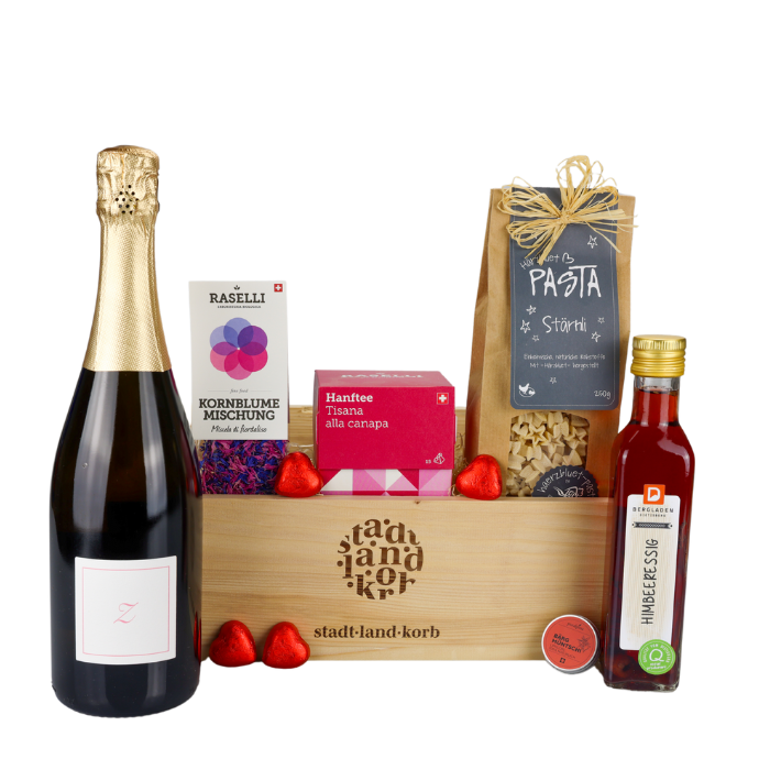 Dankeschön Deluxe Geschenkkorb vor weisssem Hintergrund befüllt mit Tsürischum, essbare Kornblumen, Hanftee, Himbeeressig, Stärnli Pasta und Lindt Herzen