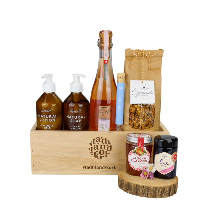 Glanz & Genuss Alkoholfrei Geschenkkorb vor weissem Hintergrund befüllt mit Soeder Natural Lotion & Natural Soap, Tröpfel der Dritte, Blütenzauber, Granola, Hong und Konfitüre