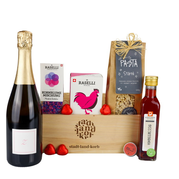 Mama Deluxe Geschenkkorb vor weissem Hintergrund befüllt mit Zürischum, essbare Kornblumen, Bio Raselli Tee, Stärnli Pasta, HImbeeressig und Lippgloss