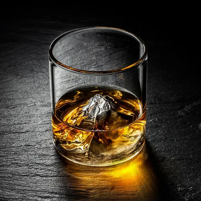 On the Rocks Matterhorn Whiskyglas und Cocktailglas Mood Bild - befüllt auf Schwarzem Stein Untergrund.