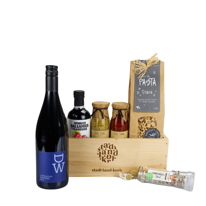 Rotwein & Genuss Geschenkkorb vor weissem Hintergrund befüllt mit DW Rotwein Himbeer Balsamico, Olivenpesto, Tomatenpesto, Stärnli Pasta, Chrüsimüsi Salz